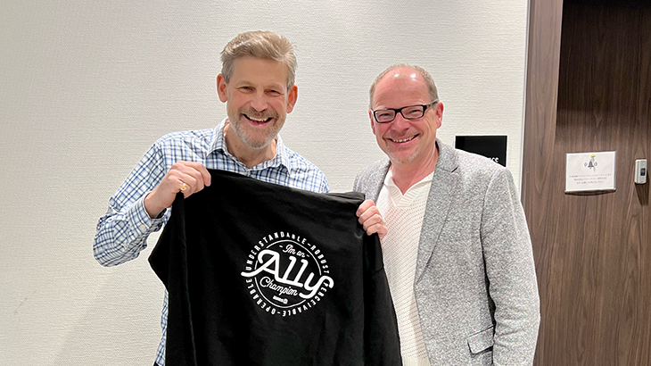 Duff Johnson wird bei der PDF Week in Tokio mit unserem A11y Champion Hoody ausgezeichnet  Er hält einen A11Y Champion Hoodie in die Höhe, daneben steht Markus Erle.